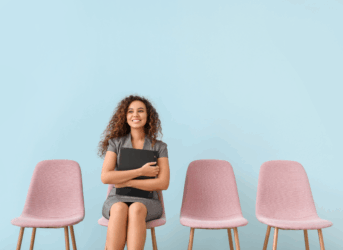 Diverse Woman recruited for a job interview sitting in spring colored chair waiting for hiring manager. Spring Recruitment Strategies.